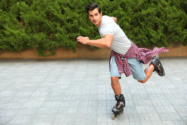 Knappe jonge man roller schaatsen buitenshuis. Recreatieve activiteit — Stockfoto