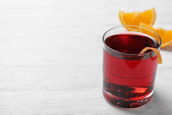 Verre de savoureux cocktail rafraîchissant avec écorce d'orange sur table en bois. Espace pour le texte — Photo