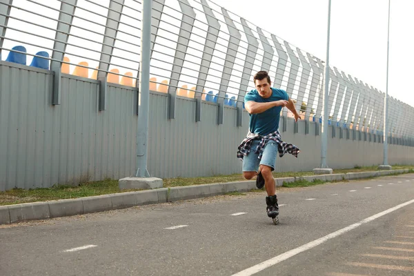 Handsome young man roller skating outdoors. Recreational activity