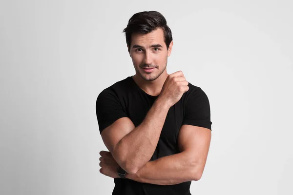 Portrait of handsome young man in black t-shirt on grey background — Stock Photo, Image