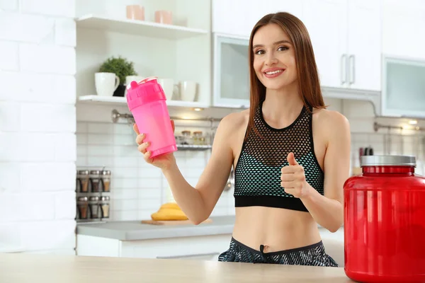 Mutfakta protein shake şişesi ile genç kadın