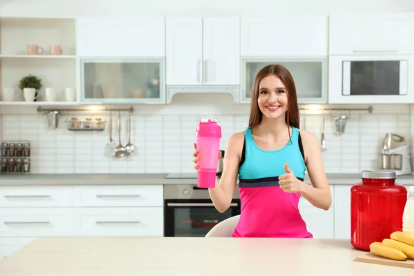 Giovane donna con bottiglia di frullato proteico in cucina — Foto Stock