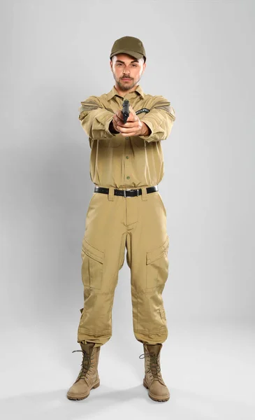 Male security guard in uniform with gun on grey background