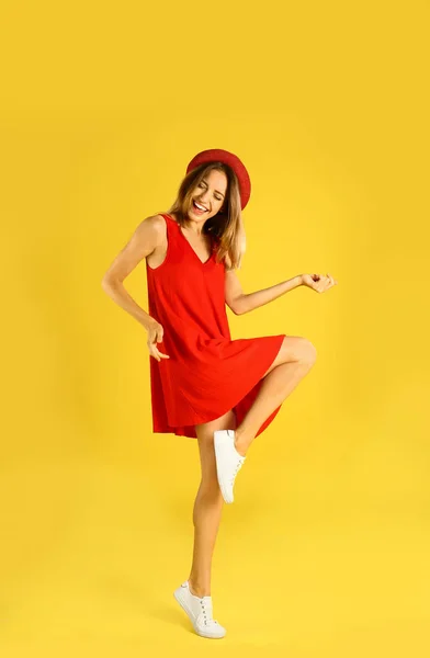 Sarı arka planda dans kırmızı elbiseli güzel genç kadın — Stok fotoğraf