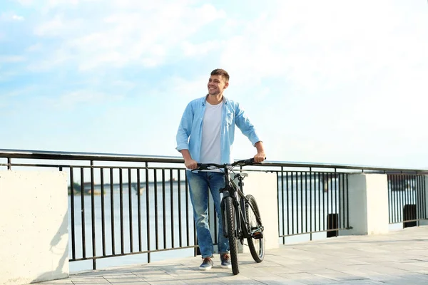 Красивий чоловік з сучасним велосипедом біля річки — стокове фото