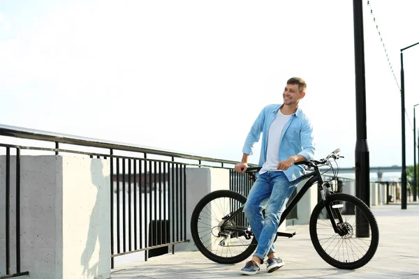 Красивий чоловік з сучасним велосипедом біля річки — стокове фото