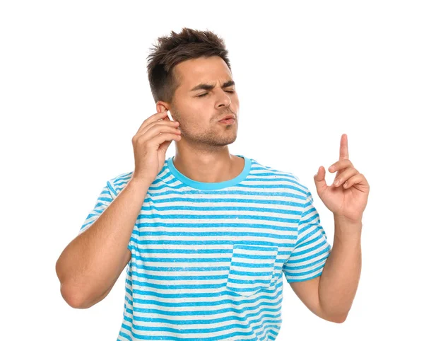 Emotional young man listening to music through wireless earphones on white background — Stock Photo, Image