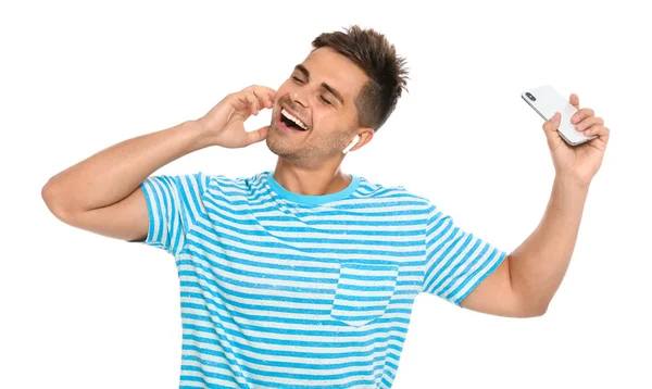 Щасливий молодий чоловік зі смартфоном, який слухає музику через бездротові навушники на білому тлі — стокове фото