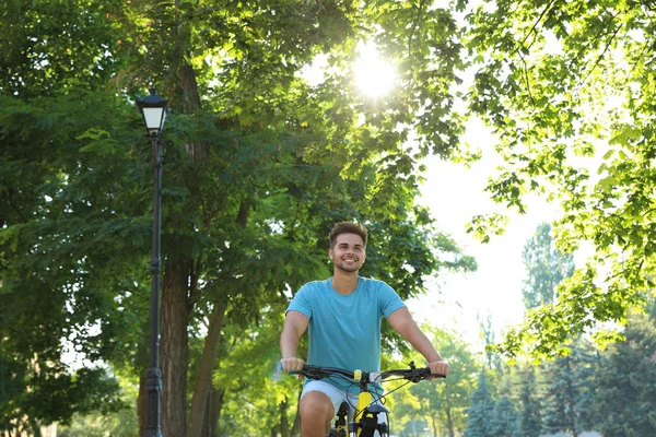Красивий молодий чоловік їде на велосипеді на міській вулиці, низький кут зору — стокове фото