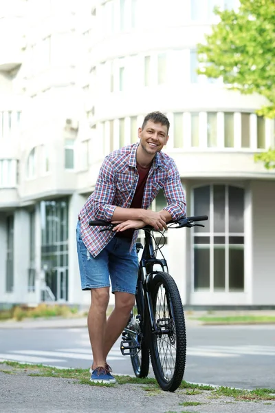 Красивий чоловік з сучасним велосипедом на міській вулиці — стокове фото