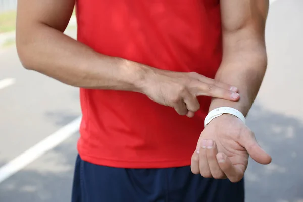 Jovem verificando pulso após o treinamento ao ar livre, close-up — Fotografia de Stock