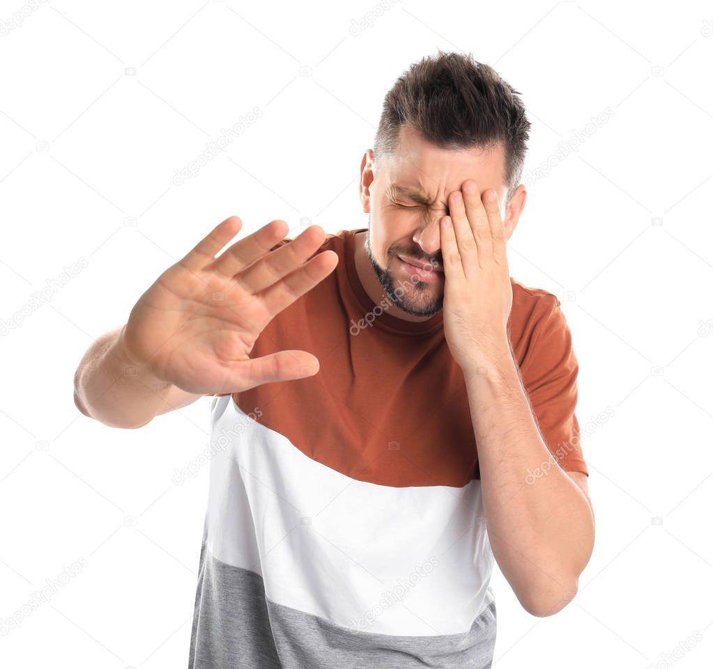 Man covering eye while being blinded on white background