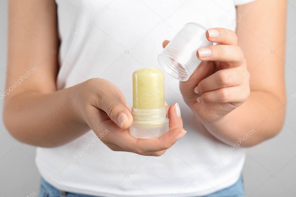 Young woman holding natural crystal alum stick deodorant, closeup