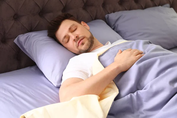 Un bel homme dormant sur un oreiller à la maison. Au lit. — Photo