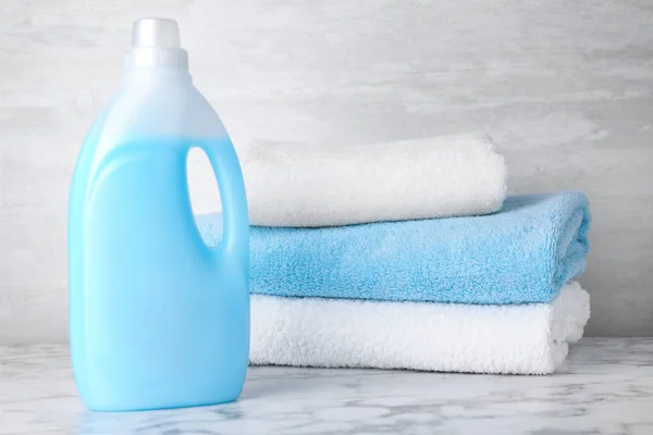 Bottle of laundry detergent and towels on marble table, space for text — Stock Photo, Image
