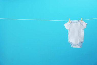 Bebek onesie mavi arka plan, metin için alan karşı giysi hattı asılı. Çamaşır günü