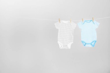 Açık gri arka plan, metin için alan karşı giysi hattı asılı farklı bebek onesies. Çamaşır günü