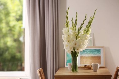 Güzel beyaz gladiolus çiçek, resim ve bardak odada ahşap masada, metin için alan ile Vazo