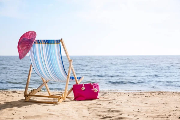 Espreguiçadeira, chapéu e saco na areia perto do mar, espaço para texto. objetos de praia — Fotografia de Stock
