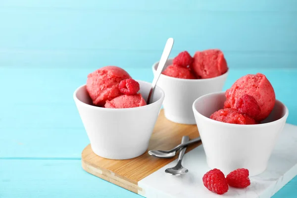 Cuencos con delicioso helado de frambuesa en la mesa de madera azul claro — Foto de Stock