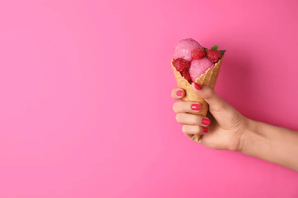 Žena držící kuželovitý kužel s lahodnou malinovou zmrzlinou na růžovém pozadí, uzavřena. Místo pro text — Stock fotografie