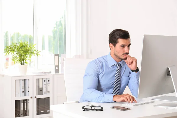 Jovem bonito trabalhando com computador à mesa no escritório — Fotografia de Stock