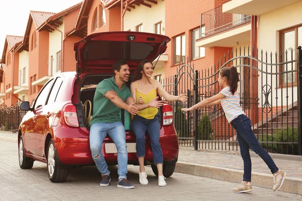 Linda chica corriendo a sus padres cerca de coche familiar en la calle — Foto de Stock