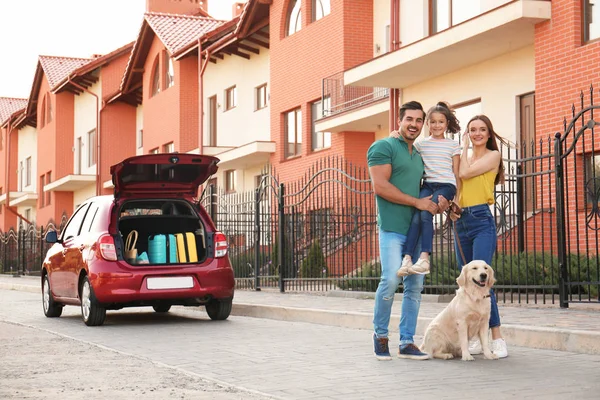 Famille heureuse avec leur chien près de la voiture dans la rue — Photo