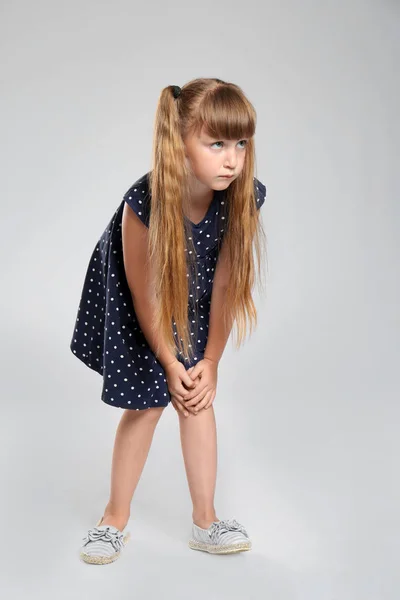 Ganzkörperporträt eines kleinen Mädchens mit Knieproblemen auf grauem Hintergrund — Stockfoto