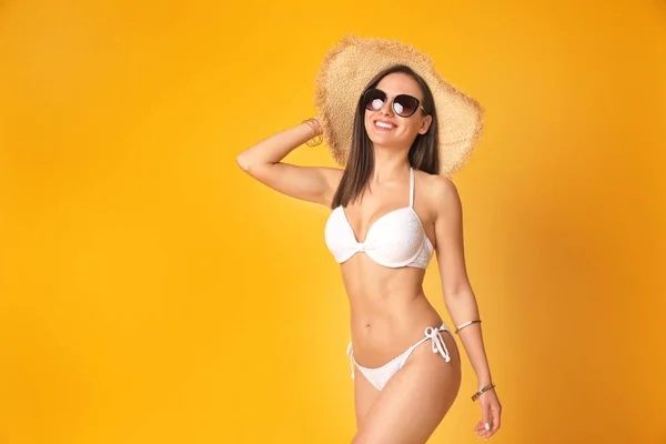 Mooie sexy vrouw met slank lichaam in stijlvolle witte bikini op oranje achtergrond, ruimte voor tekst — Stockfoto