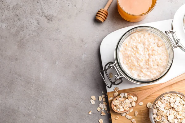 Handmade face mask, oatmeal and honey on grey table, flat lay. Space for text — Stock Photo, Image