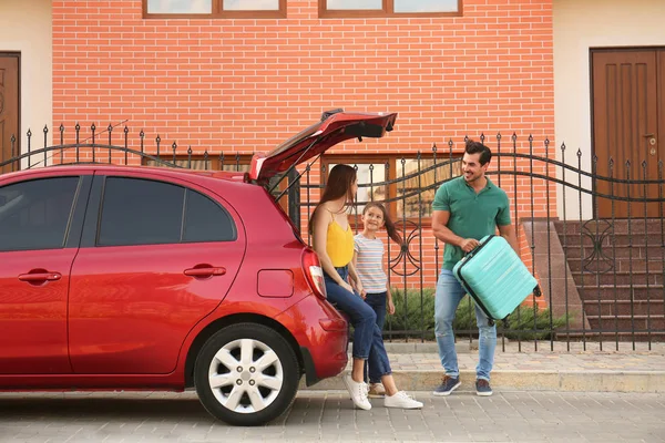 Famille heureuse avec valise près de leur voiture dans la rue — Photo