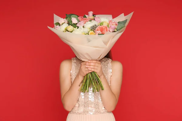 Fiatal nő gazdaság szép virág csokor vörös háttér — Stock Fotó