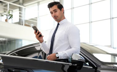 Modern bayilik araba yakınında telefon ile genç adam