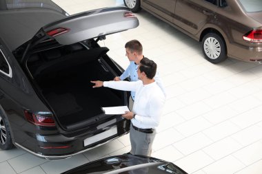 Modern otomobil bayiliğinde müşteri ile çalışan genç satıcı, yukarıda görünümü