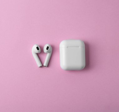 Modern kablosuz kulaklıklar ve pembe arka plan üzerinde şarj durumda, düz yatıyordu. Metin için alan