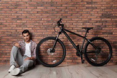 Kapalı tuğla duvar yakınında modern bisiklet ile Yakışıklı genç adam