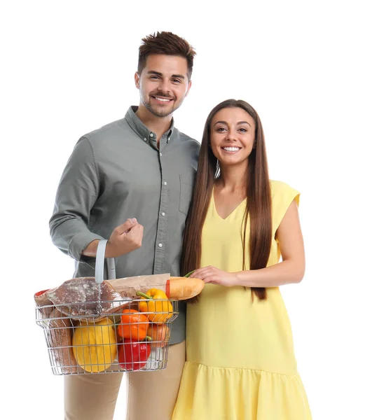 Mladý pár s nákupním košíkem plný produktů izolovaných na bílém — Stock fotografie