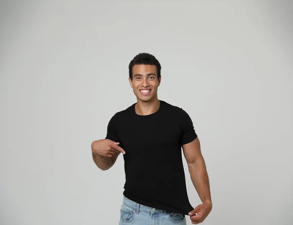 Pohledný mladý afroamerický muž na prázdném tričku na světlém pozadí. Prostor pro návrh — Stock fotografie