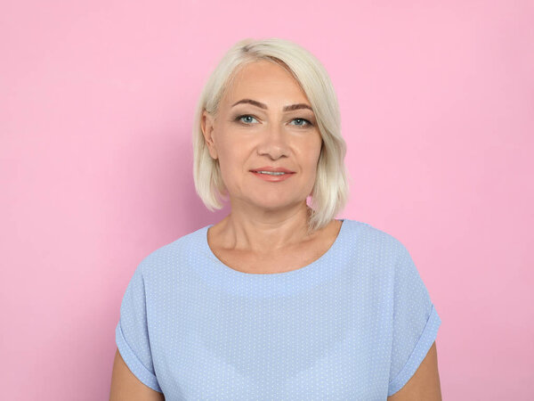 Портрет зрелой женщины с красивым лицом на розовом фоне
