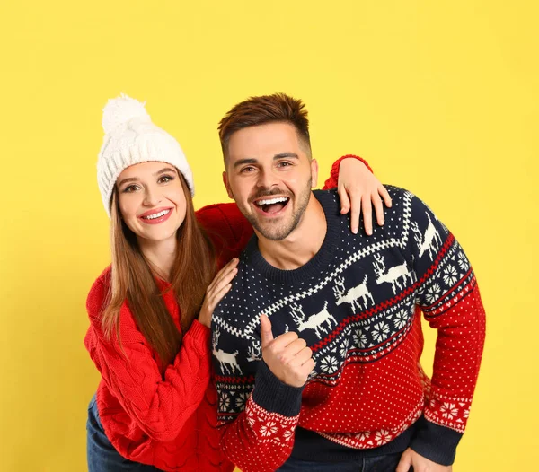 Pareja vistiendo suéteres de Navidad sobre fondo amarillo — Foto de Stock