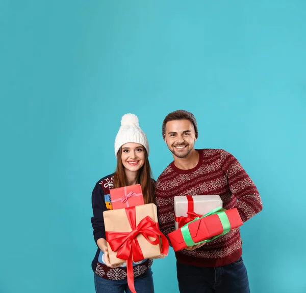 Casal em camisolas de Natal com caixas de presente no fundo azul — Fotografia de Stock