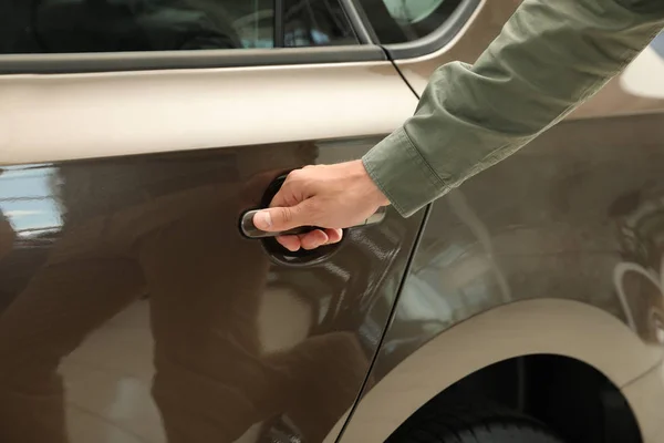 Jonge man het openen van auto deur in moderne autodealer, close-up — Stockfoto