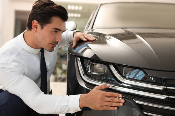 Jonge man die nieuwe auto controleert in modern dealer — Stockfoto