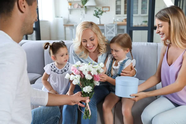 Familia feliz con niños pequeños felicitando a la mujer madura en la sala de estar — Foto de Stock