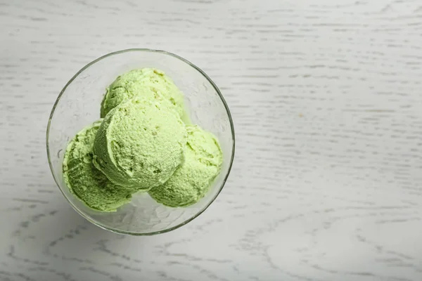 Köstliches grünes Eis serviert in Dessertschüssel auf weißem Holztisch, Draufsicht. Raum für Text — Stockfoto