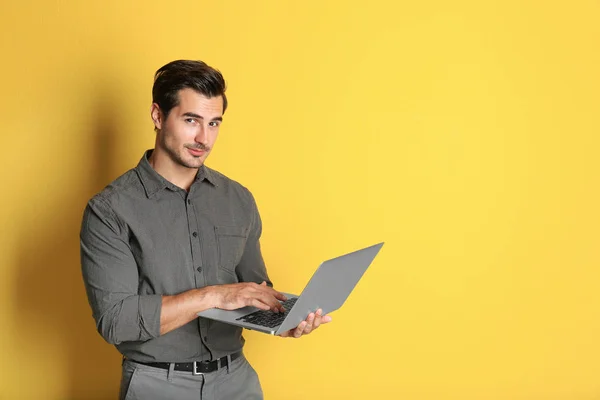 Jeune professeur masculin avec ordinateur portable sur fond jaune. Espace pour le texte — Photo