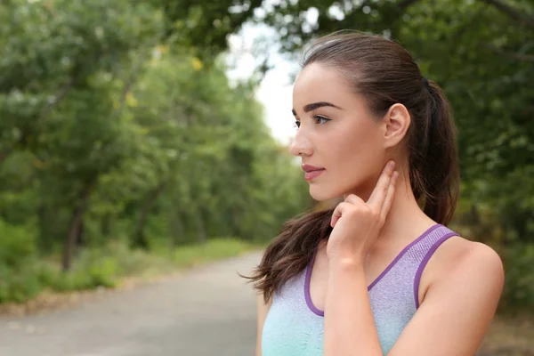 Mujer joven revisando el pulso después de entrenar en el parque. Espacio para texto — Foto de Stock