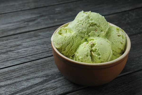 Νόστιμο πράσινο παγωτό σερβίρεται σε κεραμικό μπολ σε ξύλινο τραπέζι — Φωτογραφία Αρχείου