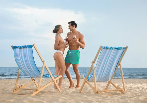 愉快的年轻夫妇在海边海滩的甲板椅子附近 — 图库照片